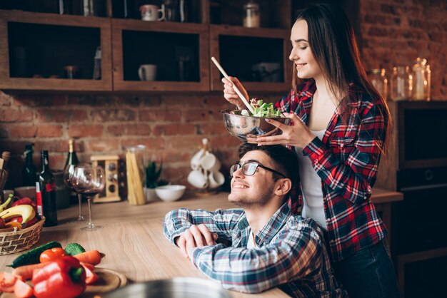 Heureux couple cuisine salade de légumes ensemble, préparation du dîner romantique. La famille prépare des aliments sains dans la cuisine