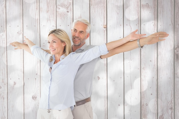 Heureux couple debout avec les bras tendus contre des cercles de lumière sur fond gris