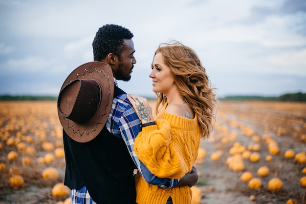 Heureux couple debout dans un champ de citrouilles