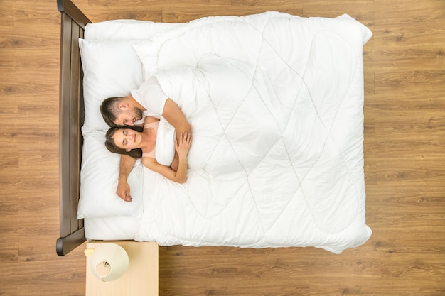 L'heureux couple dort sur le lit. Vue d'en-haut