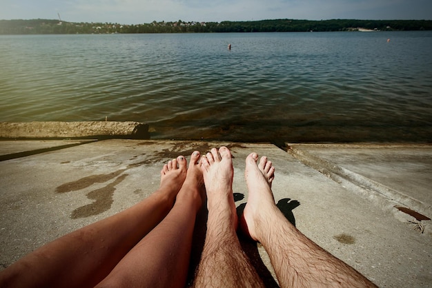 Photo heureux couple élégant jambes bronzer à l'espace de vacances d'été à la plage pour le texte