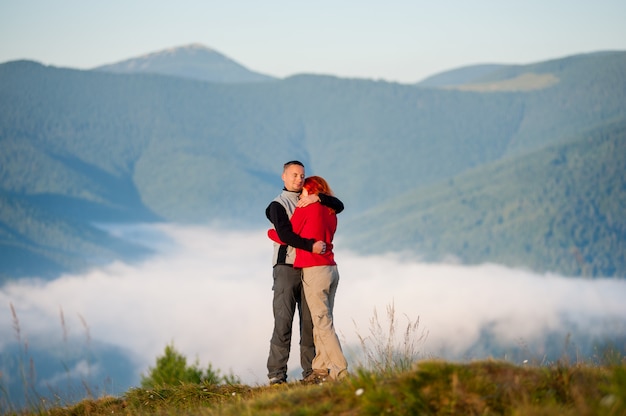 Heureux couple embrassant contre le magnifique paysage de montagne