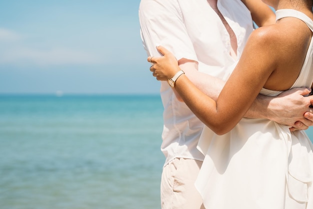 Heureux couple embrassant ensemble et dansant sur la plage tropicale