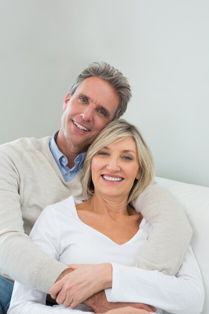 Heureux couple embrassant tout en étant assis sur le canapé à la maison