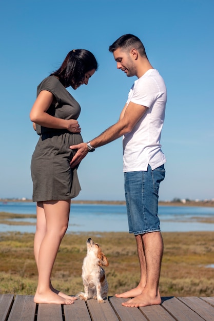 Heureux couple enceinte avec petit chien à la plage avec petit chien à la plage à la plage à la plage