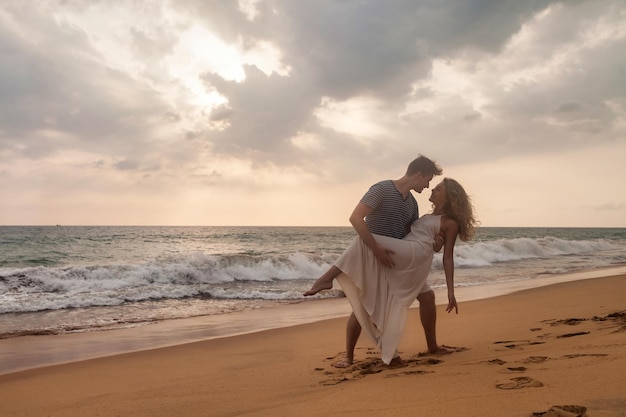 Heureux couple ensemble français s'embrasser sur la plage de sable tropicale au coucher du soleil de mer