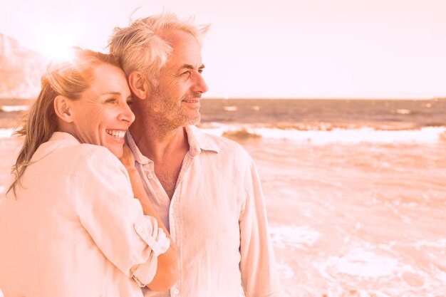 Photo heureux couple étreignant sur la plage face à la mer par une journée ensoleillée