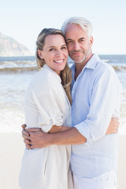 Heureux couple étreindre sur la plage en regardant la caméra