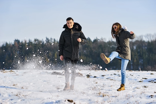 Heureux couple étreindre et rire à l'extérieur en hiver. La photo convient à la publicité des vêtements d'hiver