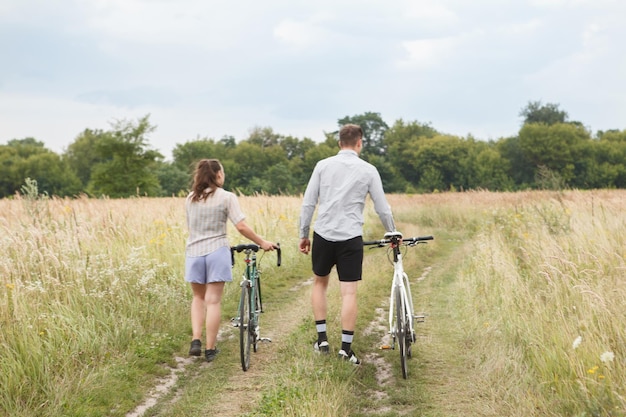 L'heureux couple faisant du vélo près du champ