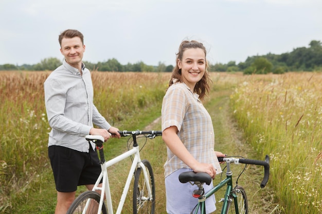 Photo l'heureux couple faisant du vélo près du champ