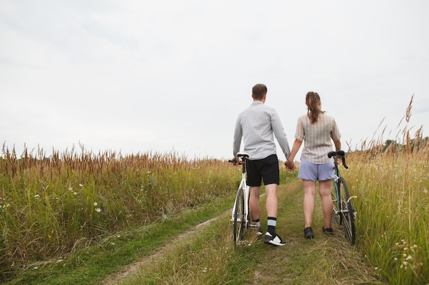 Photo l'heureux couple faisant du vélo près du champ