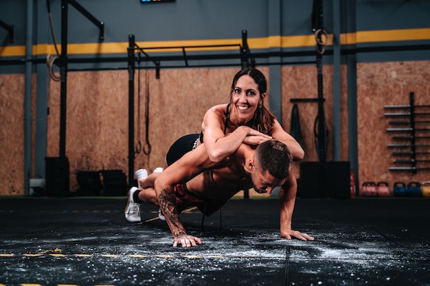 Heureux couple de fitness garçon et fille dans la trentaine travaillant dur dans une salle de sport pour augmenter les muscles