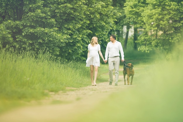 Heureux couple futurs parents sur la promenade avec le chien dans le parc