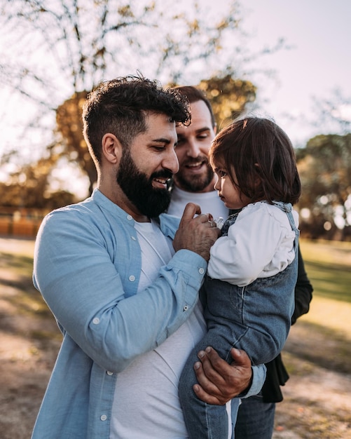 Heureux couple gay avec leur fille dans les bras Son père lui donne la tétine