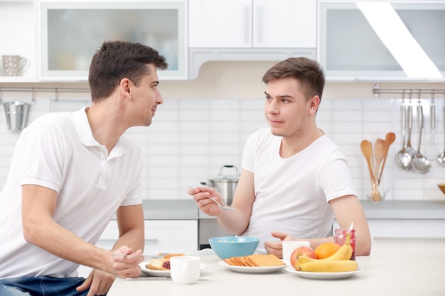 Heureux couple gay prenant son petit déjeuner dans la cuisine