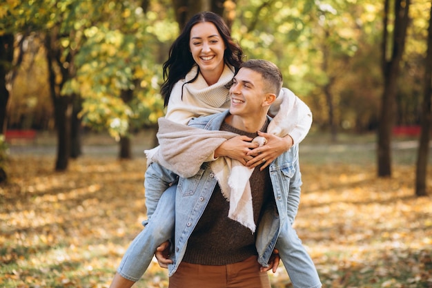 Heureux couple homme tenant une femme derrière son dos et s'amusant ensemble dans le parc en automne