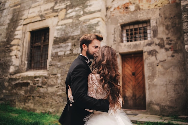 Photo heureux couple de jeunes mariés étreignant et s'embrassant dans la vieille rue de la ville européenne, magnifique mariée en robe de mariée blanche avec beau marié. jour de mariage.