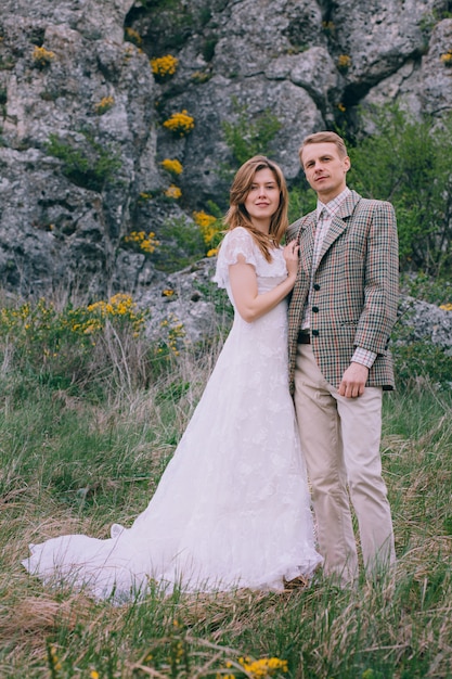 Heureux couple de jeunes mariés près des rochers