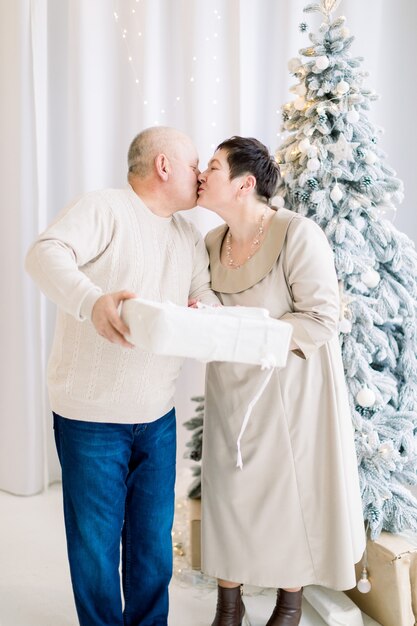 Heureux couple joyeux embrassant tenant une boîte cadeau blanche