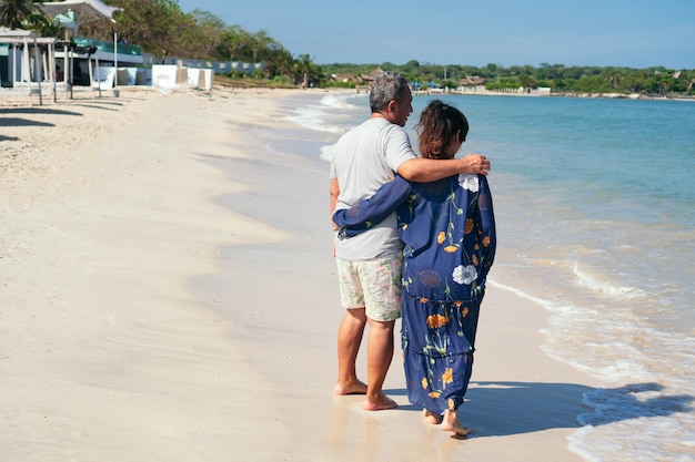 Heureux couple latin plus âgé debout sur une plage