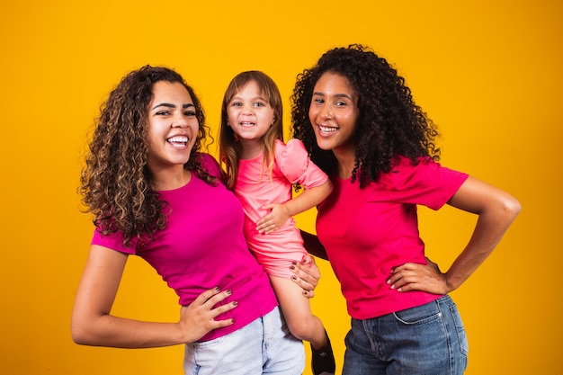 Heureux couple de lesbiennes avec petite fille adoptée sur fond de couleur