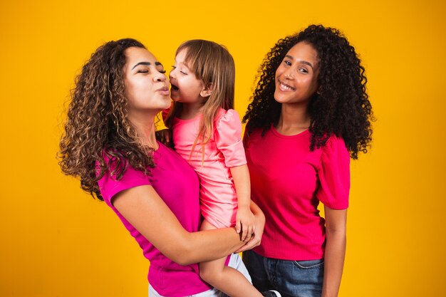 Heureux couple de lesbiennes avec petite fille adoptée sur fond de couleur