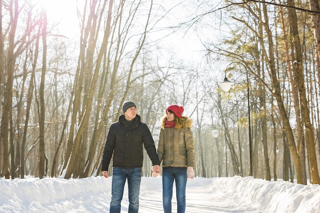 Heureux couple marchant dans une forêt enneigée en hiver.