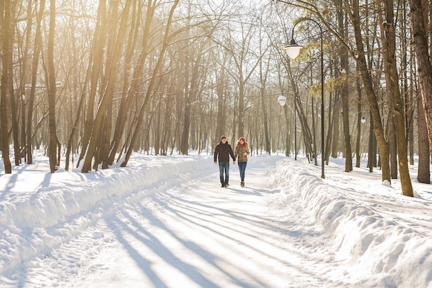 Heureux couple marchant dans une forêt enneigée en hiver.