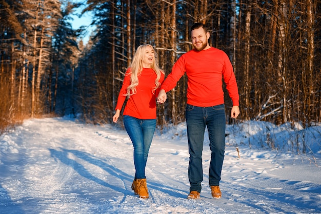 Heureux couple marchant dans la forêt enneigée