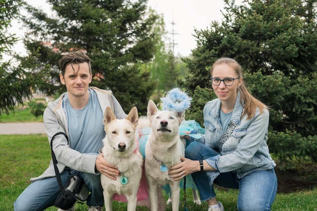 Heureux couple marchant avec deux bergers blancs dans le parc