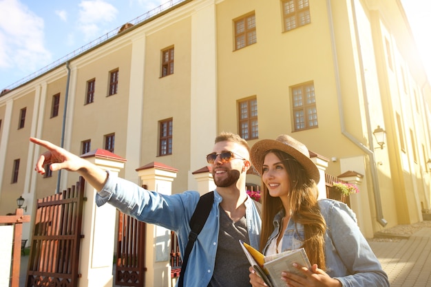 Heureux couple marchant à l'extérieur du tourisme et tenant une carte.