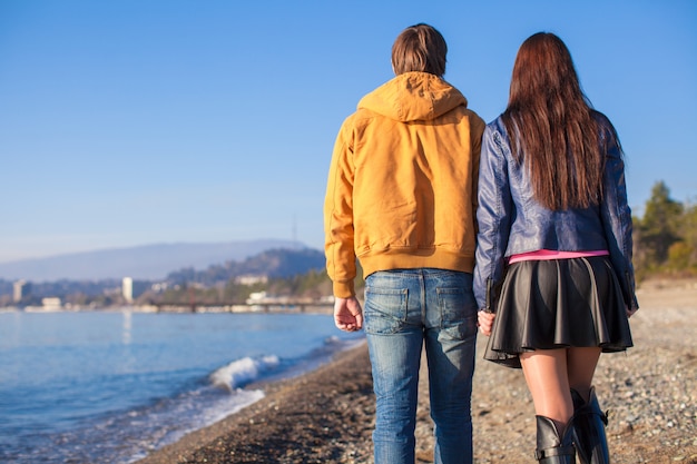 Photo heureux couple marchant sur la plage un jour d'hiver ensoleillé