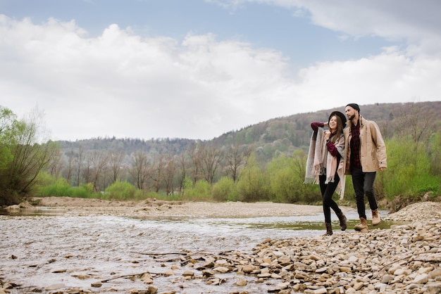 Heureux couple marchant sur la rivière dans les montagnes