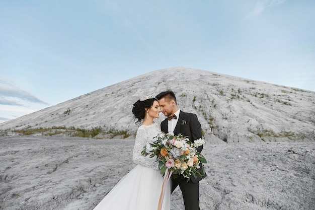 Heureux couple de mariage debout à l'extérieur sur le magnifique paysage de montagnes