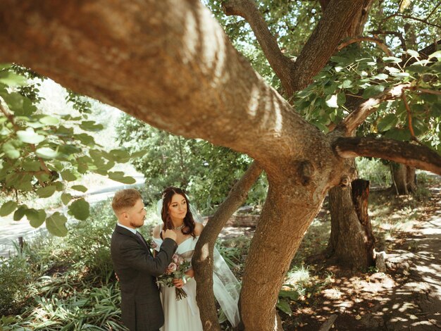 Heureux couple de mariage marchant dans un parc botanique effet grain authentique