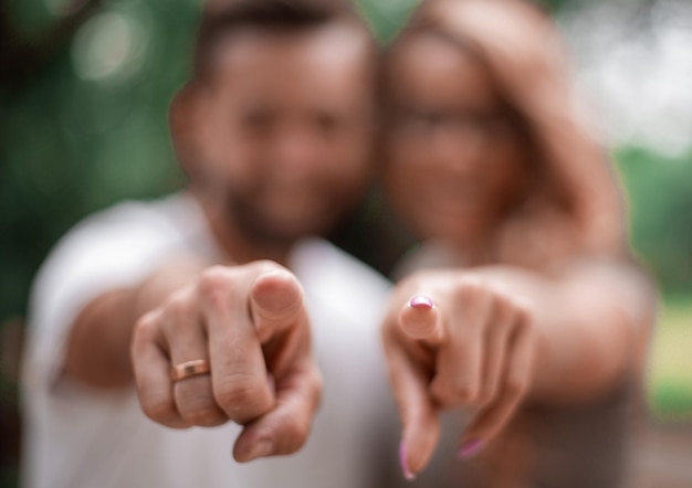 Heureux couple marié debout dans le parc et vous pointant du doigt