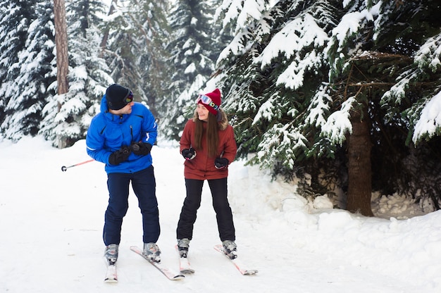 Heureux couple marié, ski dans une station de ski dans la forêt