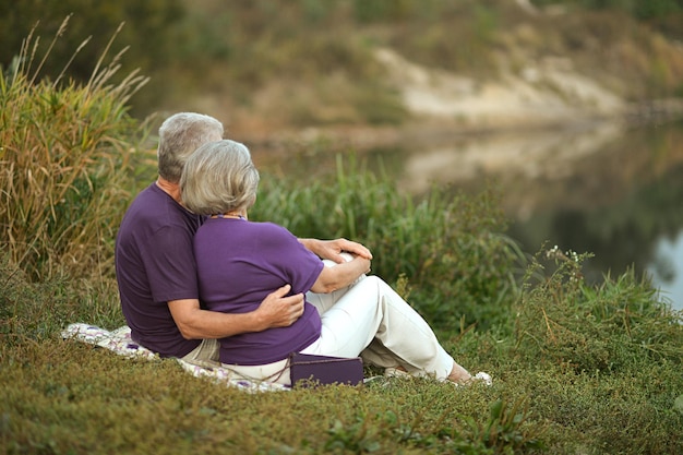 Heureux couple mature assis près d'un lac