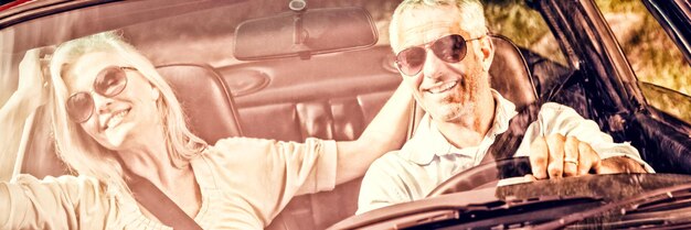 Heureux couple mature en cabriolet rouge faisant un tour aux beaux jours