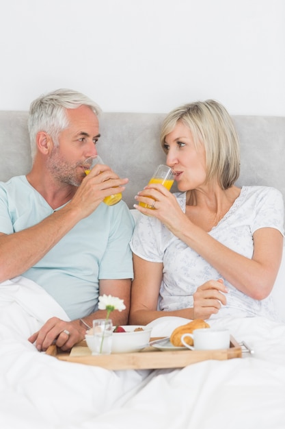 Heureux couple mature prenant son petit déjeuner au lit