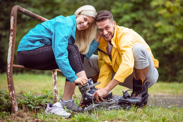 Heureux couple mettant sur les patins à roues alignées