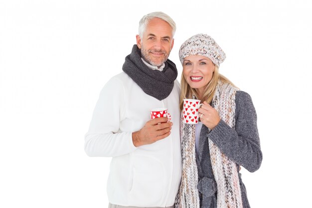 Heureux couple en mode hiver tenant des tasses