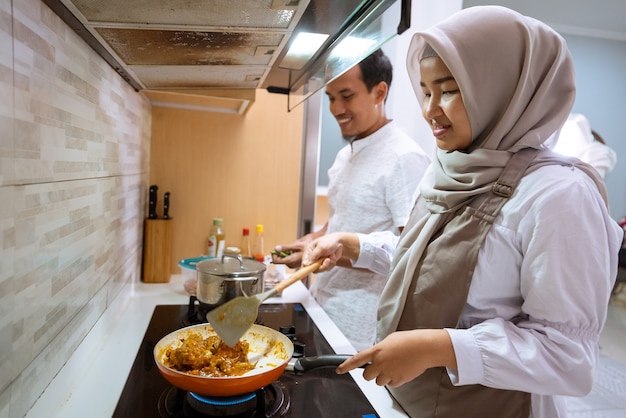 Heureux couple musulman cuisiner ensemble dans la cuisine. homme et femme préparant pour le dîner