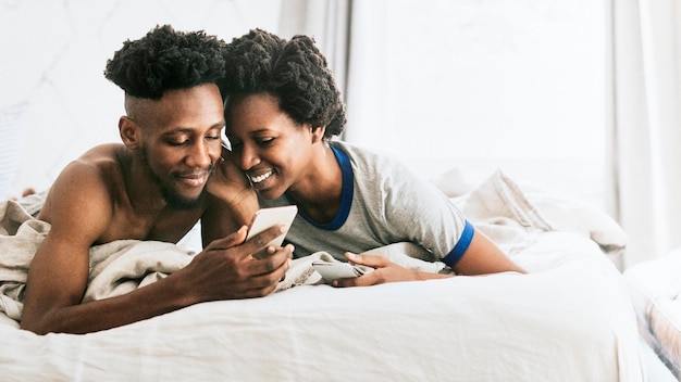 Heureux couple noir jouant sur un smartphone ensemble