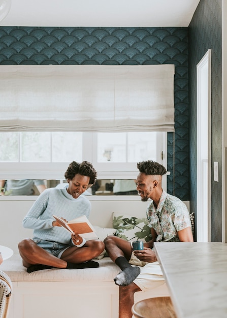 Heureux couple noir lisant un livre à la maison