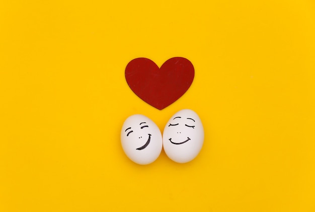 Heureux couple d'oeufs de poule face avec coeur sur fond jaune