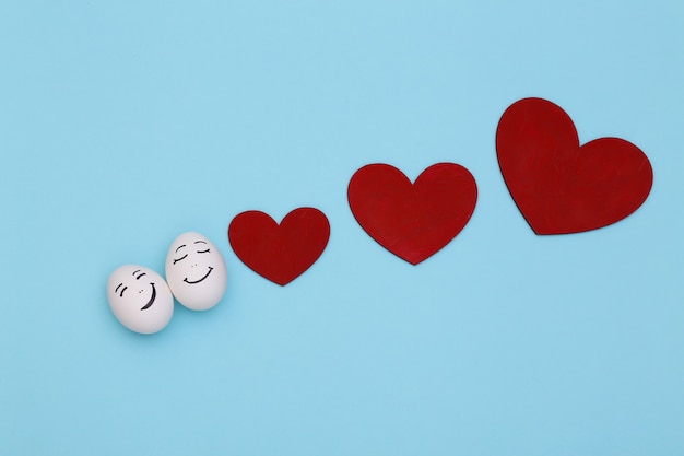 Heureux couple d'oeufs de poule face avec des coeurs sur fond bleu