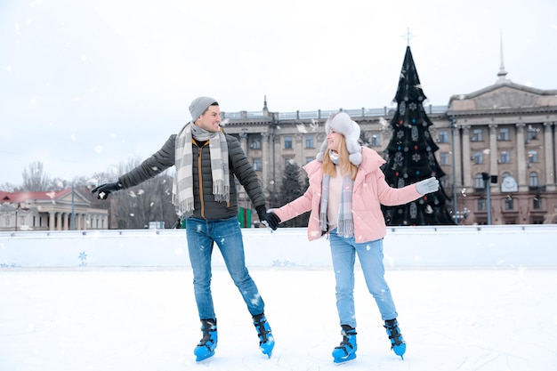 Photo heureux couple patinant le long de la patinoire à l'extérieur