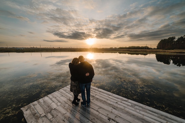 Heureux couple de personnes âgées amoureux étreignant et debout sur la jetée pendant le coucher du soleil Couple âgé regardant le coucher du soleil Bonne vieille famille marchant sur la plage au coucher du soleil Vue arrière